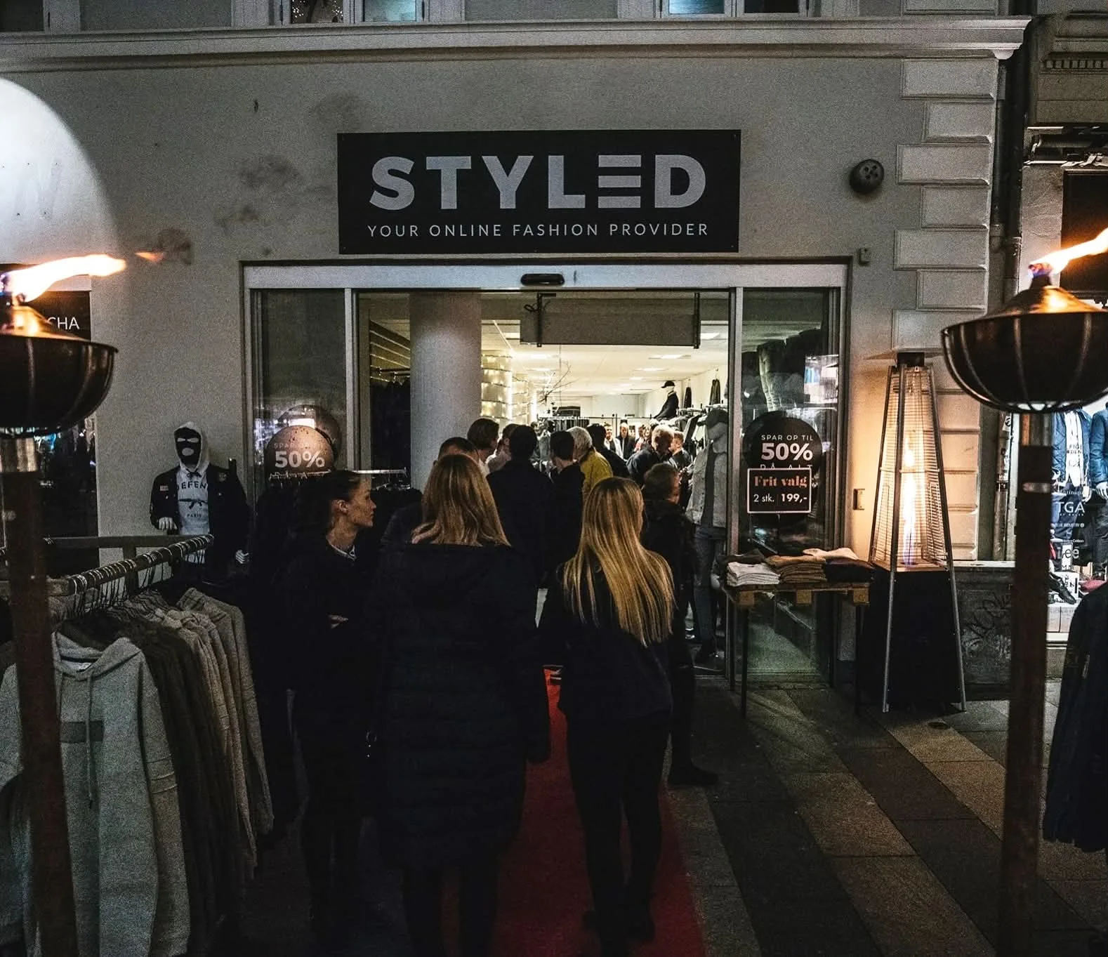 Kunder foran en oplyst butik med et stort STYLED-skilt over indgangen.